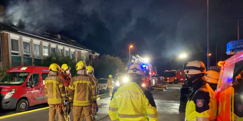 Feuerwehrleute stehen vor einem brennenden Haus